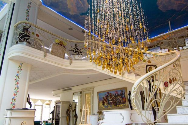 Elegant interior featuring a stunning chandelier, ornate staircase, and decorative ceiling.
