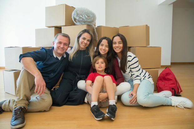 A joyful family sitting together with moving boxes in their new home.