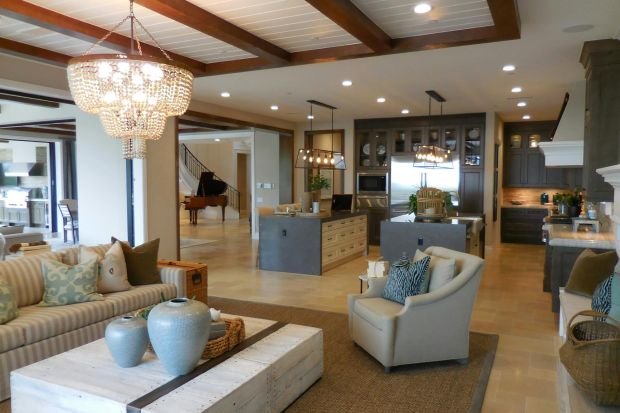 Spacious living room with elegant decor and an open kitchen area, featuring a chandelier and comfortable furnishings.