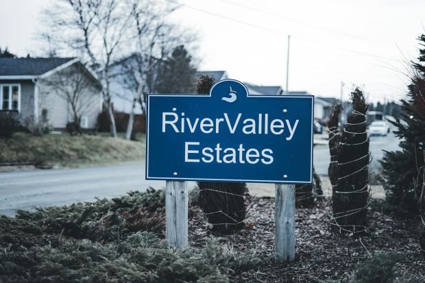 A blue sign of River Valley Estates in a suburban neighborhood setting.