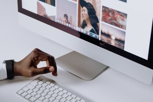 Man working on computer in modern office, viewing photography website. Clean and tech-focused environment.